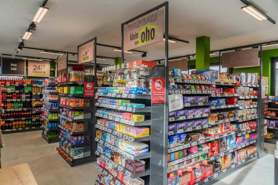 Ein Gang in einem Lebensmittelgeschäft mit Regalen, die mit Snacks, Getränken und verschiedenen verpackten Waren bestückt sind.