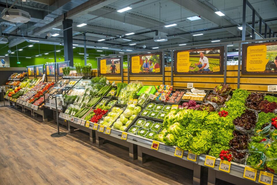 In der Gemüseabteilung eines WASGAU Supermarkts findet man eine Vielzahl von frischem Gemüse und Grünzeug, darunter Salat, Tomaten, Gurken und Paprika, die ordentlich in den Regalen angeordnet sind und deren Preisschilder unter jedem Artikel sichtbar sind.