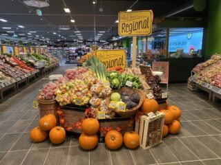 Auslage mit Kürbissen, Äpfeln, Kartoffeln und Blattgemüse in einem WASGAU Lebensmittelgeschäft mit der Aufschrift 