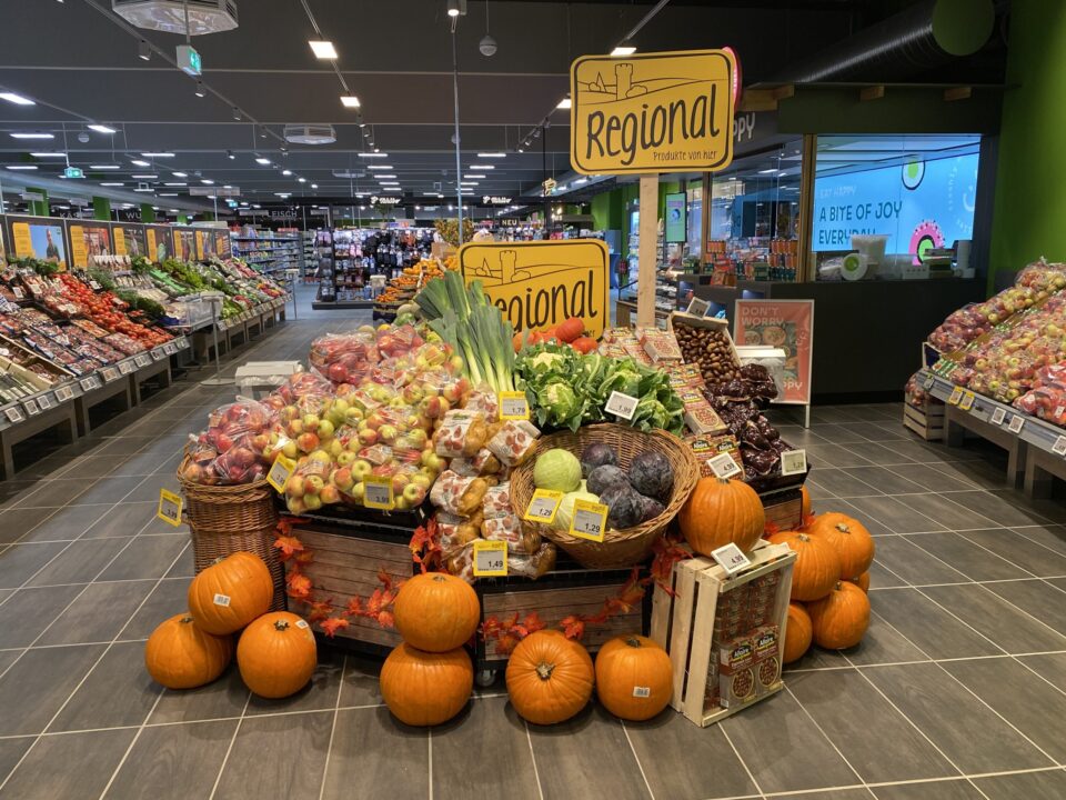Auslage mit Kürbissen, Äpfeln, Kartoffeln und Blattgemüse in einem WASGAU Lebensmittelgeschäft mit der Aufschrift 