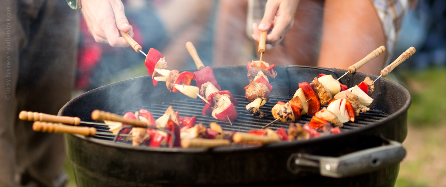 Menschen grillen Spieße mit Fleisch und Gemüse auf einem Holzkohlegrill im Freien und genießen den perfekten Prospektabend in der KW 35.