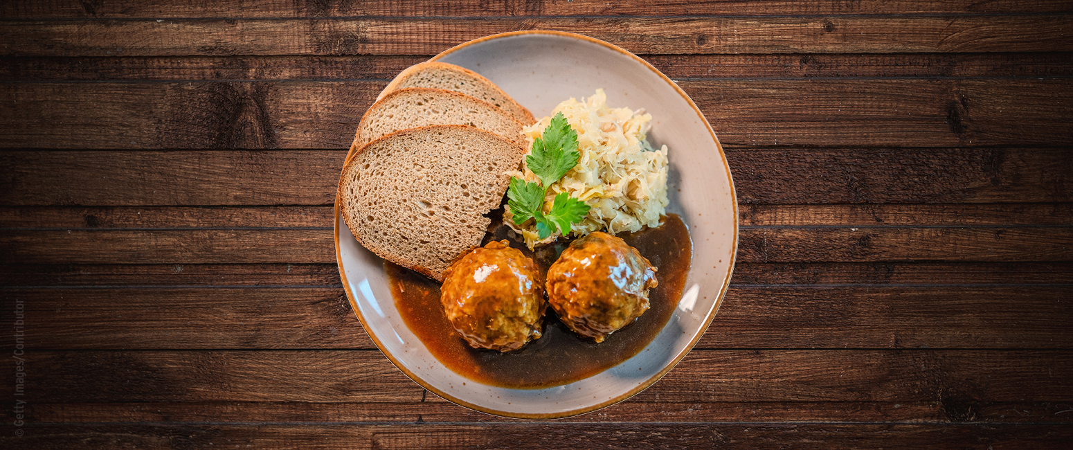 Ein Teller mit zwei Fleischbällchen in Bratensoße, Roggenbrotscheiben und einer Portion Krautsalat, garniert mit Petersilie - eine herzhafte Mahlzeit in der Prospekt KW 43.