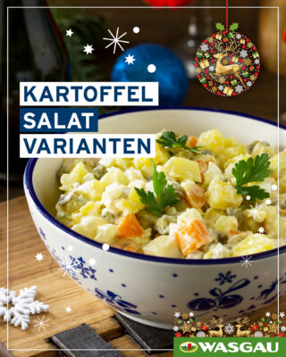 Eine Schale Kartoffelsalat, der cremige Klassiker, mit Gemüse und Kräutern steht auf einem Holztisch, im Hintergrund festliche Dekoration.
